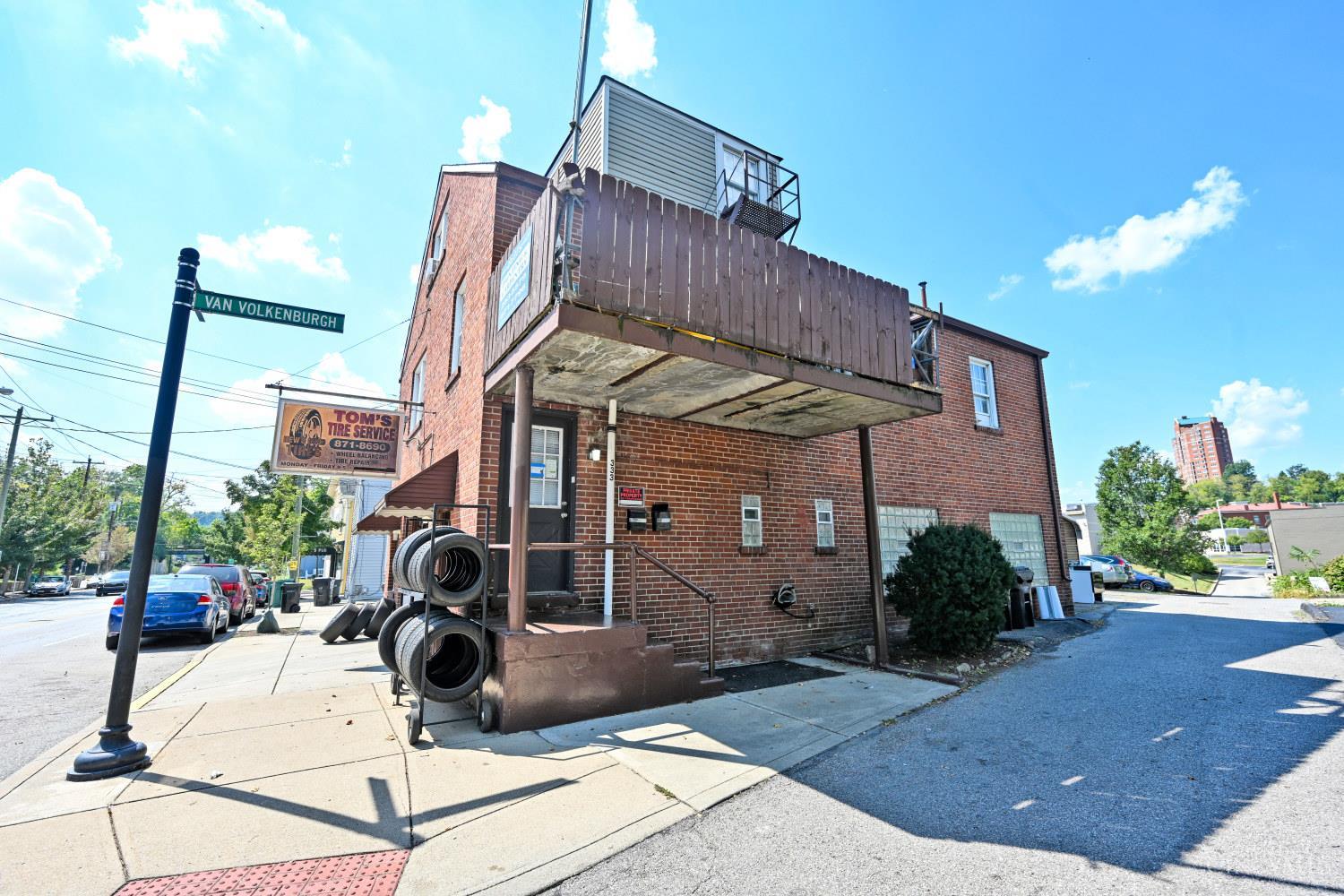Brick property with a raised wooden balcony and tire service sign at the corner.