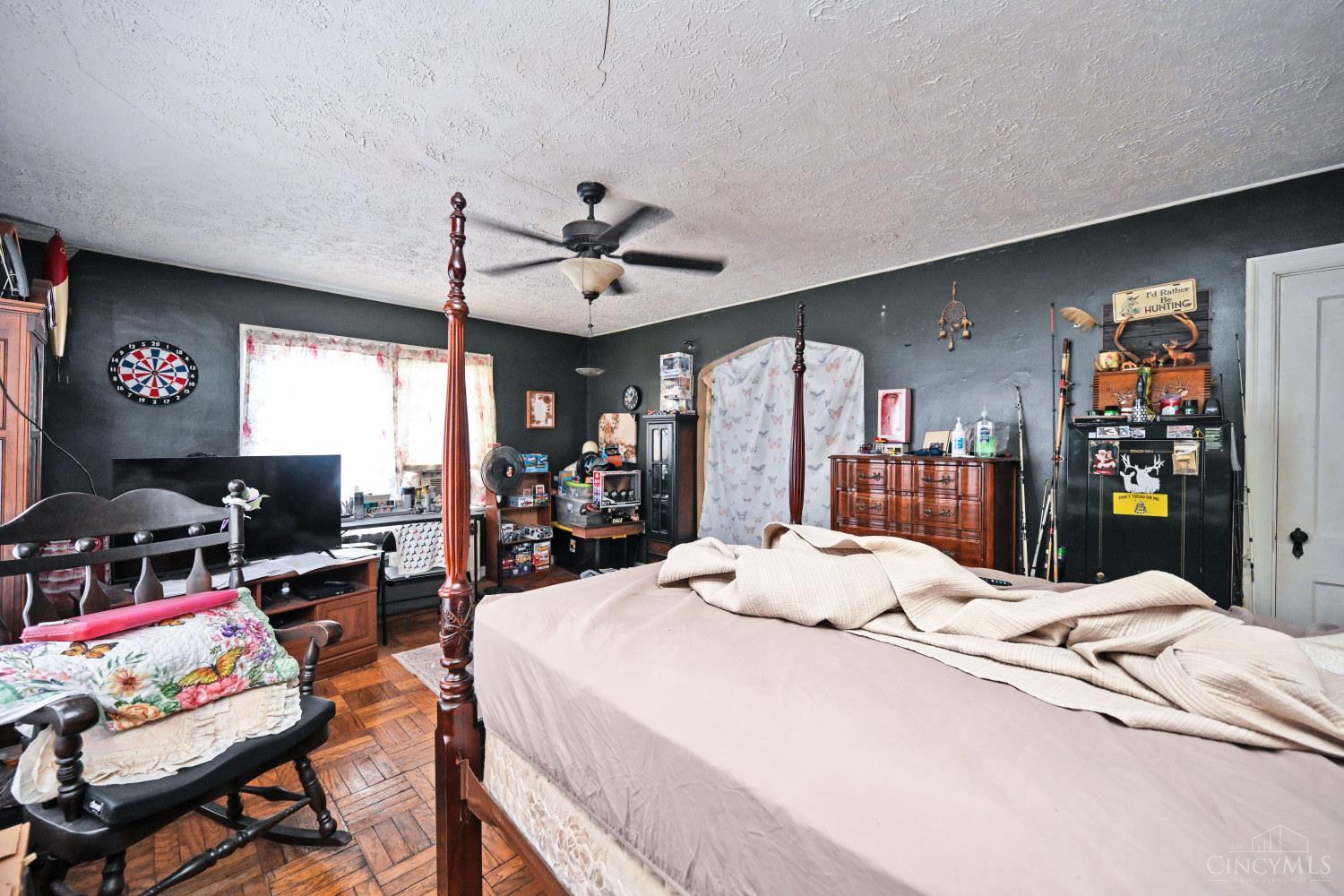 Bedroom with a four-poster bed, parquet flooring, dark walls, and hunting-themed decor.