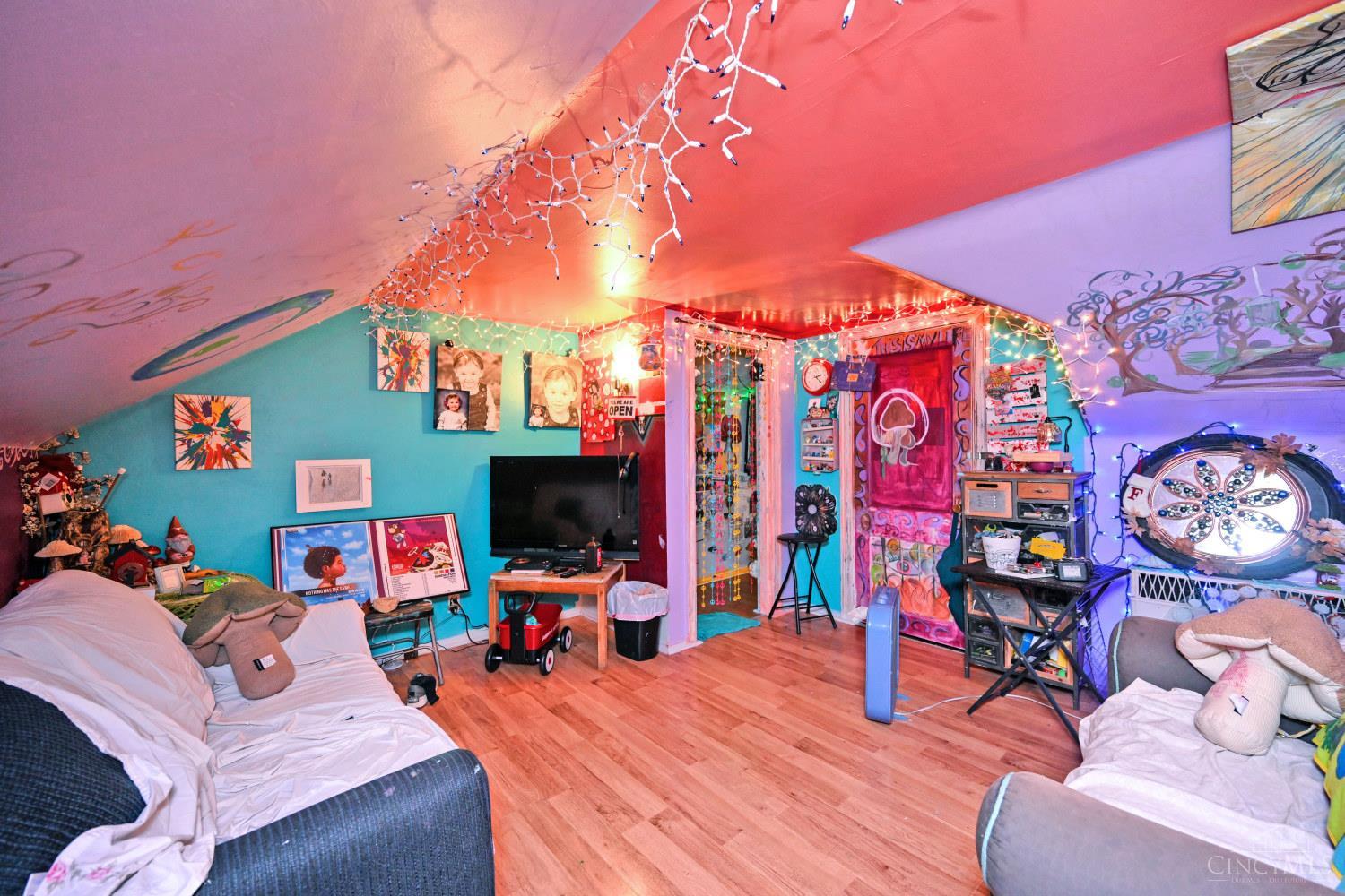 Attic living room with a sloped ceiling, colorful walls, string lights, and eclectic decor.