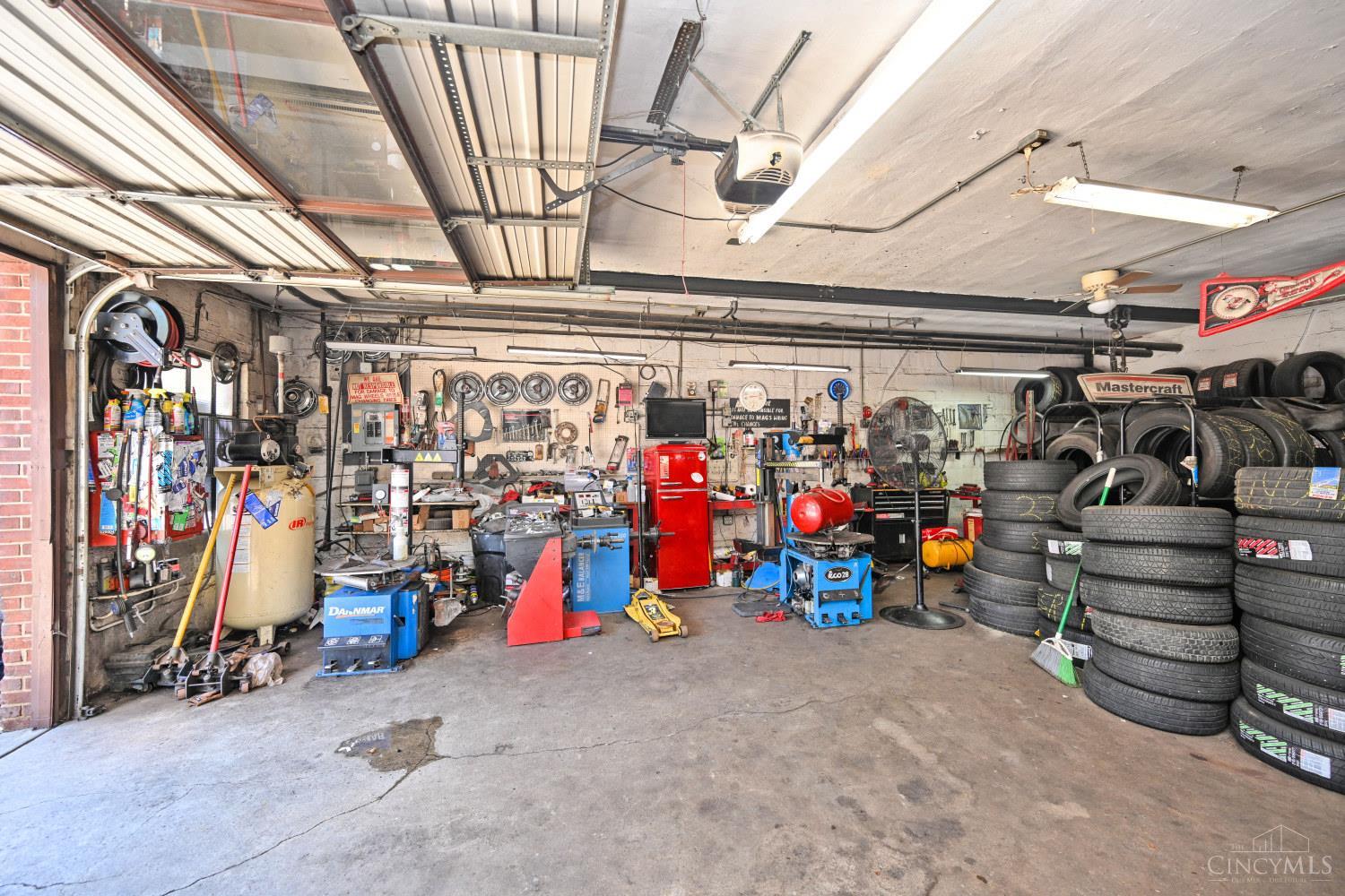 Automotive repair garage filled with tire stacks, service equipment, and workbenches.