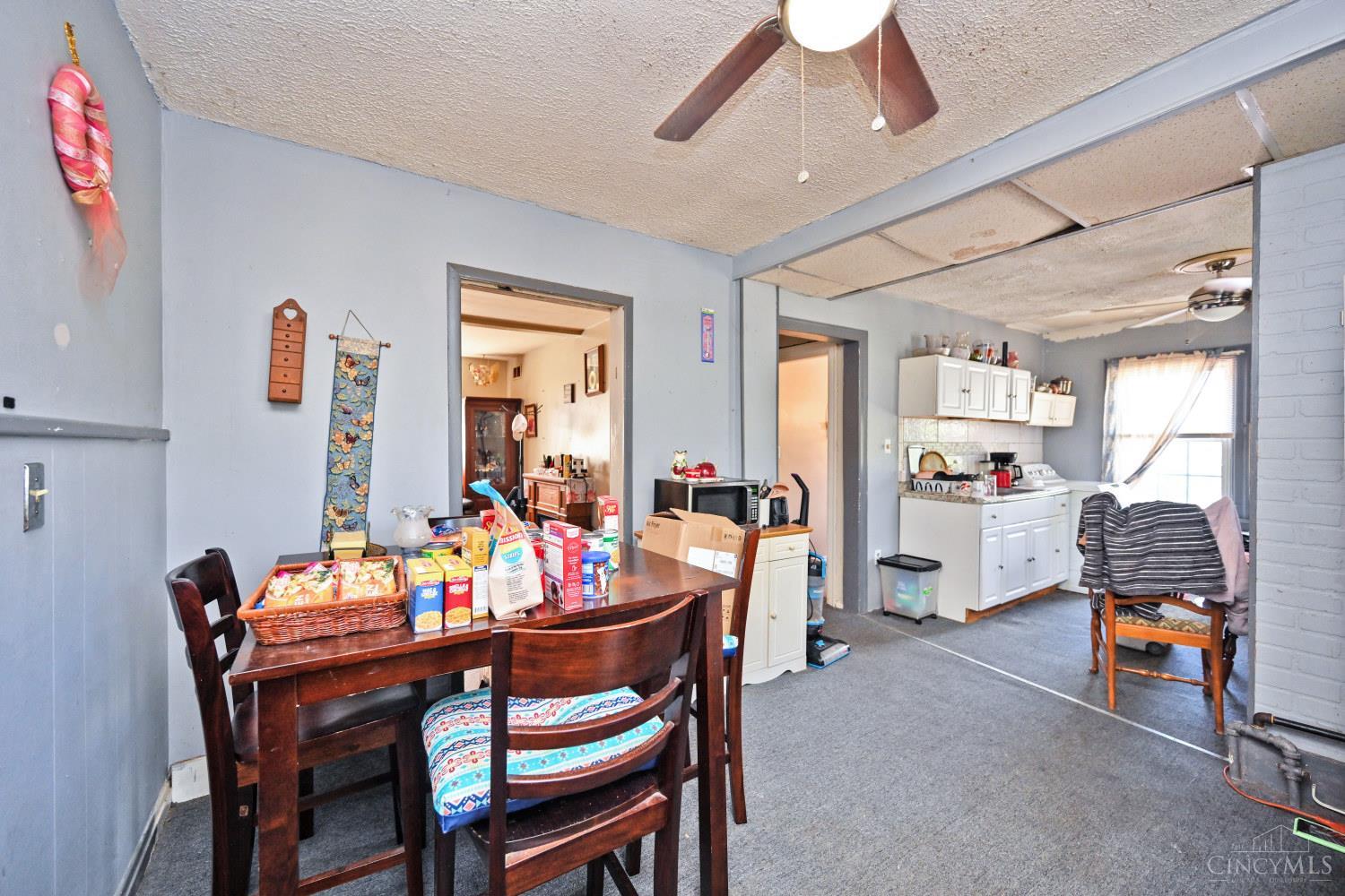Dining area with a dark wood table and an adjoining white-cabinet kitchen.