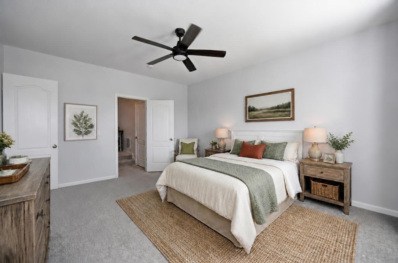 Staged bedroom with a white bed, green accents, matching bedside lamps, and a dark ceiling fan.