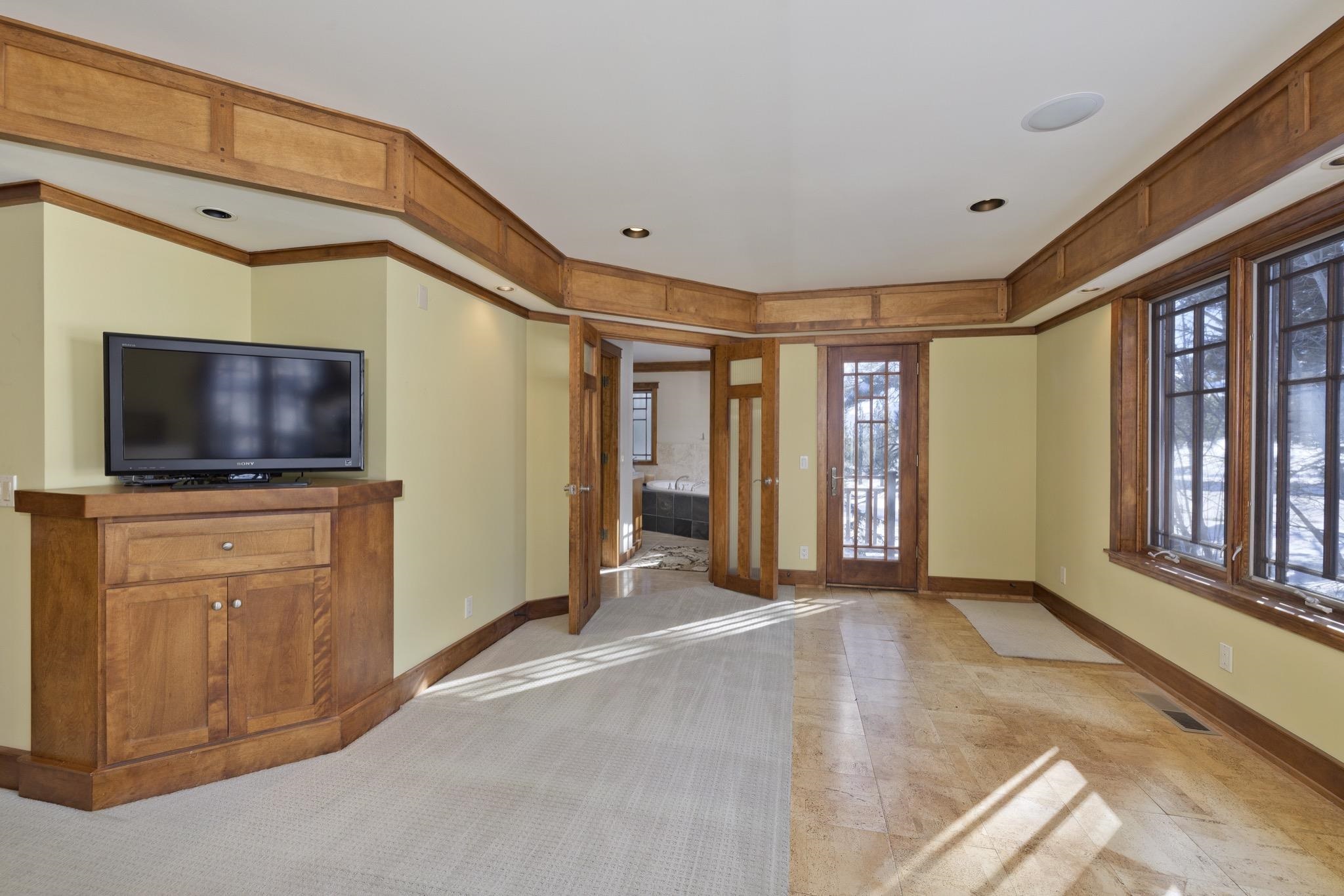 Living room with wood trim, a TV cabinet, and large windows overlooking snow.