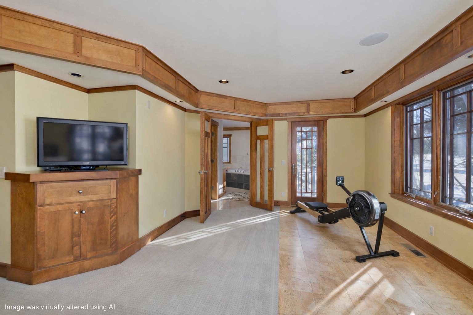 Interior room with wood trim, large windows, a TV cabinet, and a rowing machine.