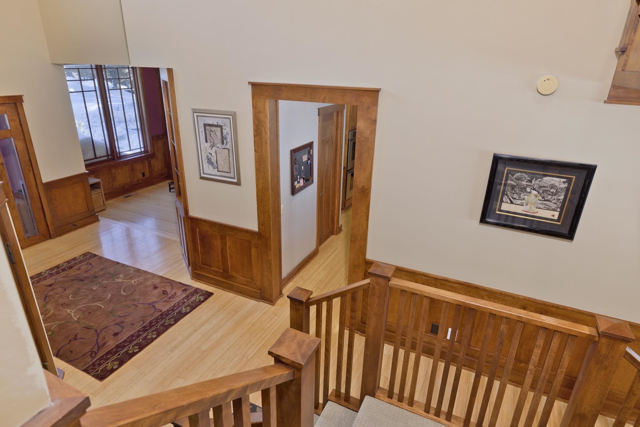 Wood-trimmed landing with a patterned rug and snowy views through adjoining room windows.