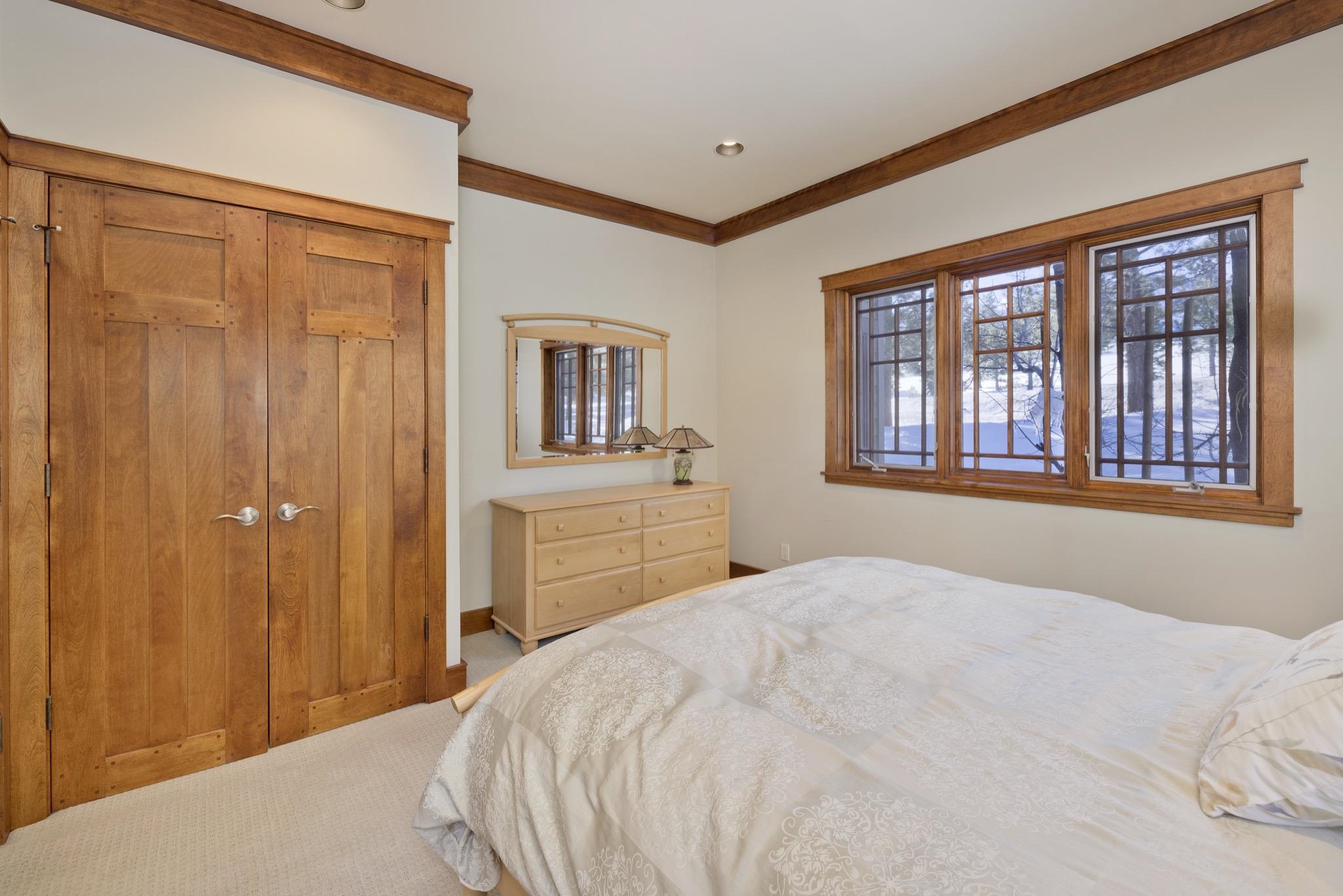 Bedroom with warm wood closet doors, a dresser, and large windows overlooking snow.