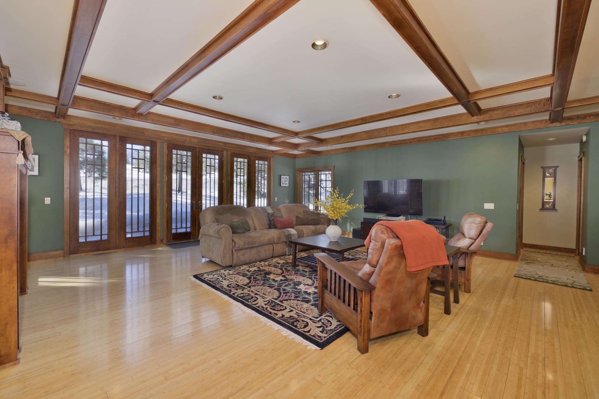 Living room with a coffered wood ceiling, green walls, and tall glass doors overlooking snow.