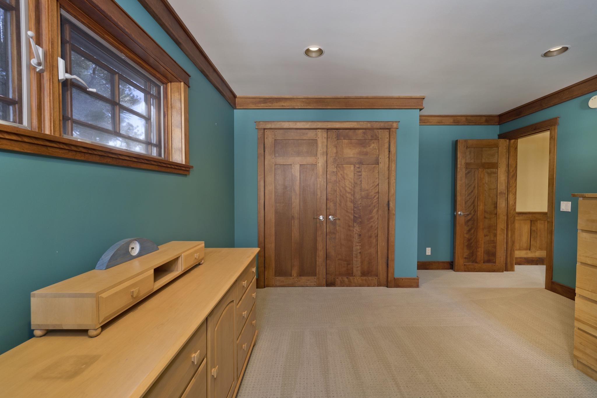Bedroom with teal walls, a built-in wooden wardrobe, and a light wood dresser.