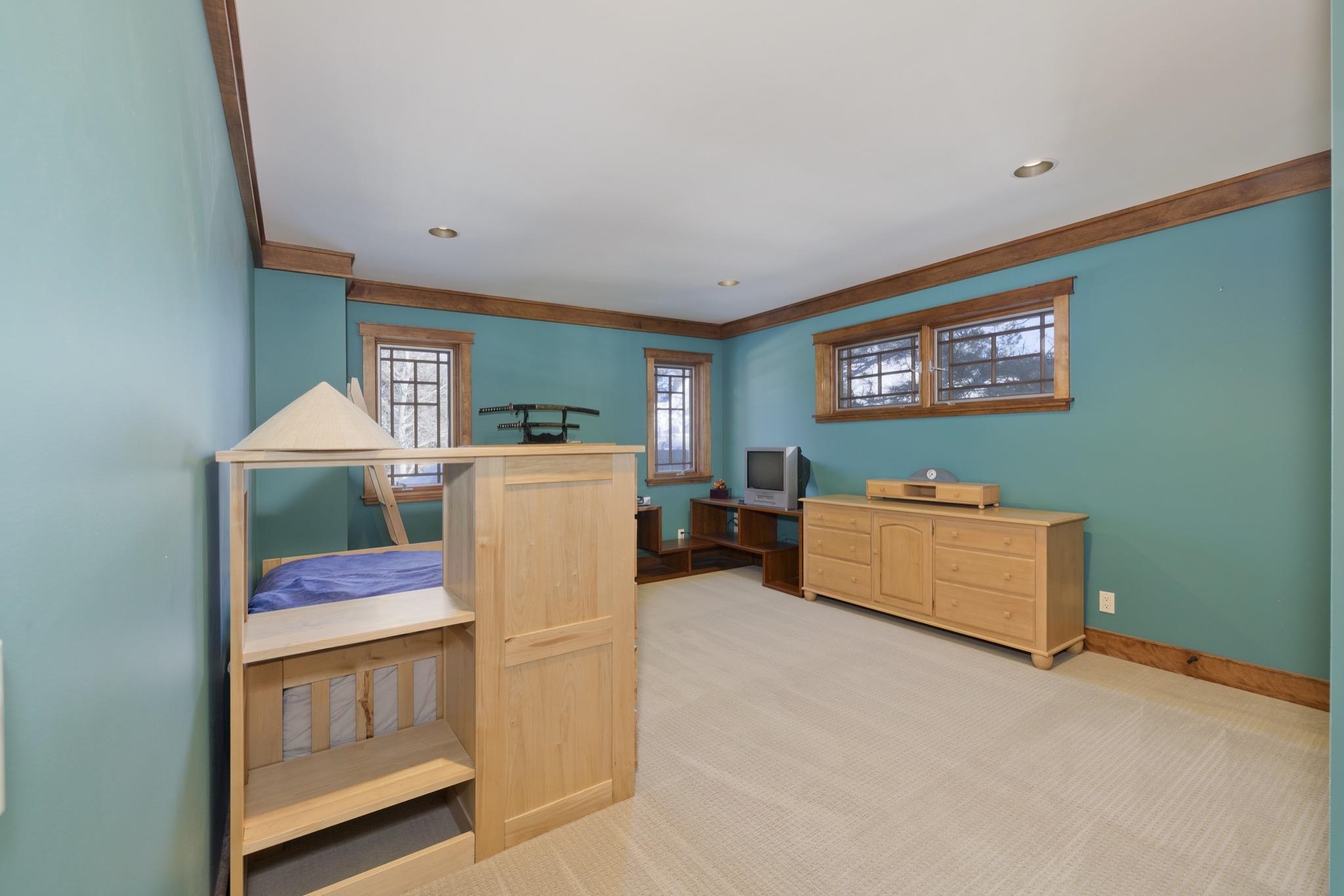 Bedroom with a wooden bunk bed, turquoise walls, and a light wood dresser.
