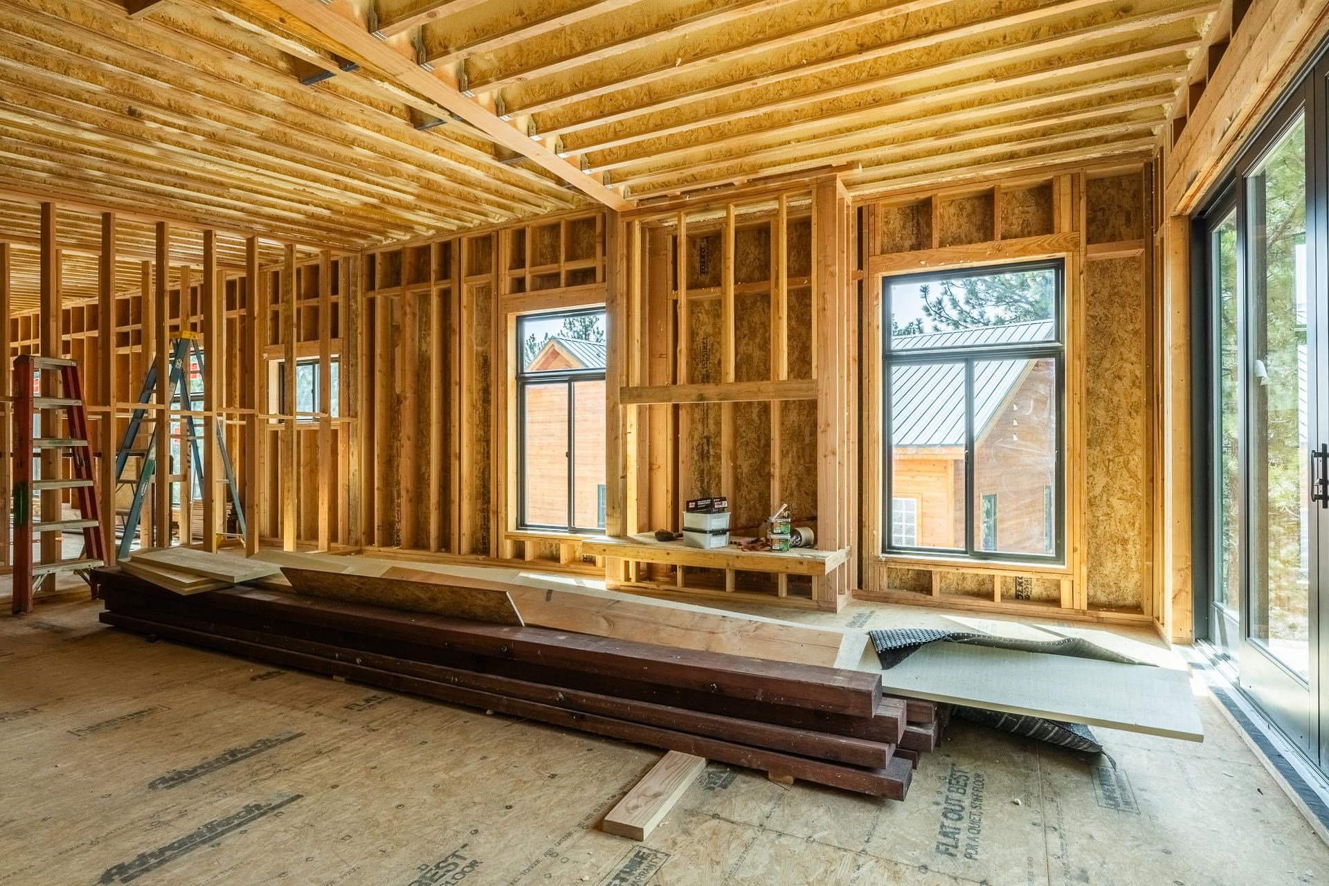 Unfinished interior with exposed timber framing, ceiling joists, and windows.