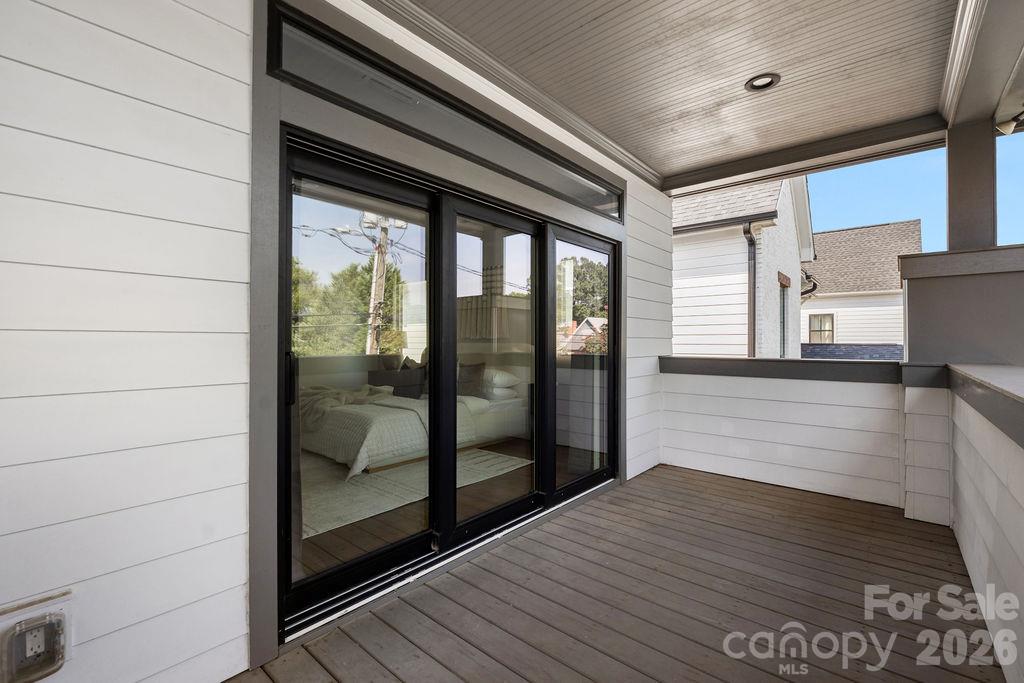 Covered deck with dark plank flooring and black-framed sliding glass doors.