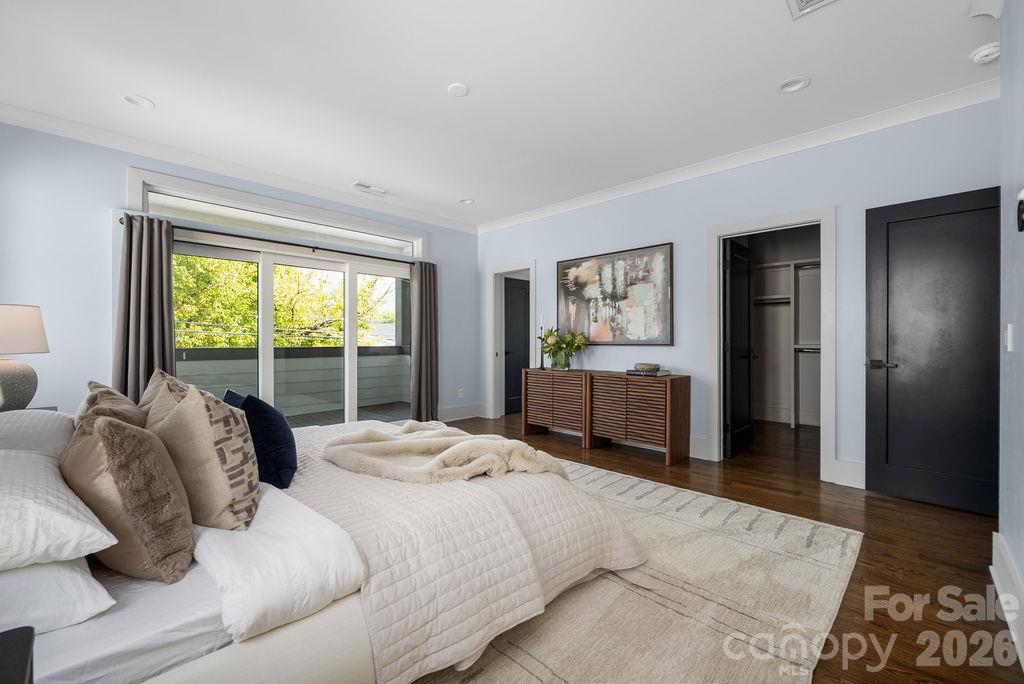 Staged bedroom with a quilted bed and sliding glass doors opening to a leafy balcony.