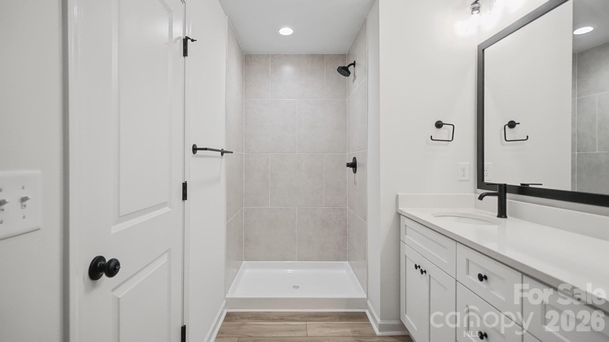 Bathroom with a gray-tiled walk-in shower, white vanity, and matte black fixtures.