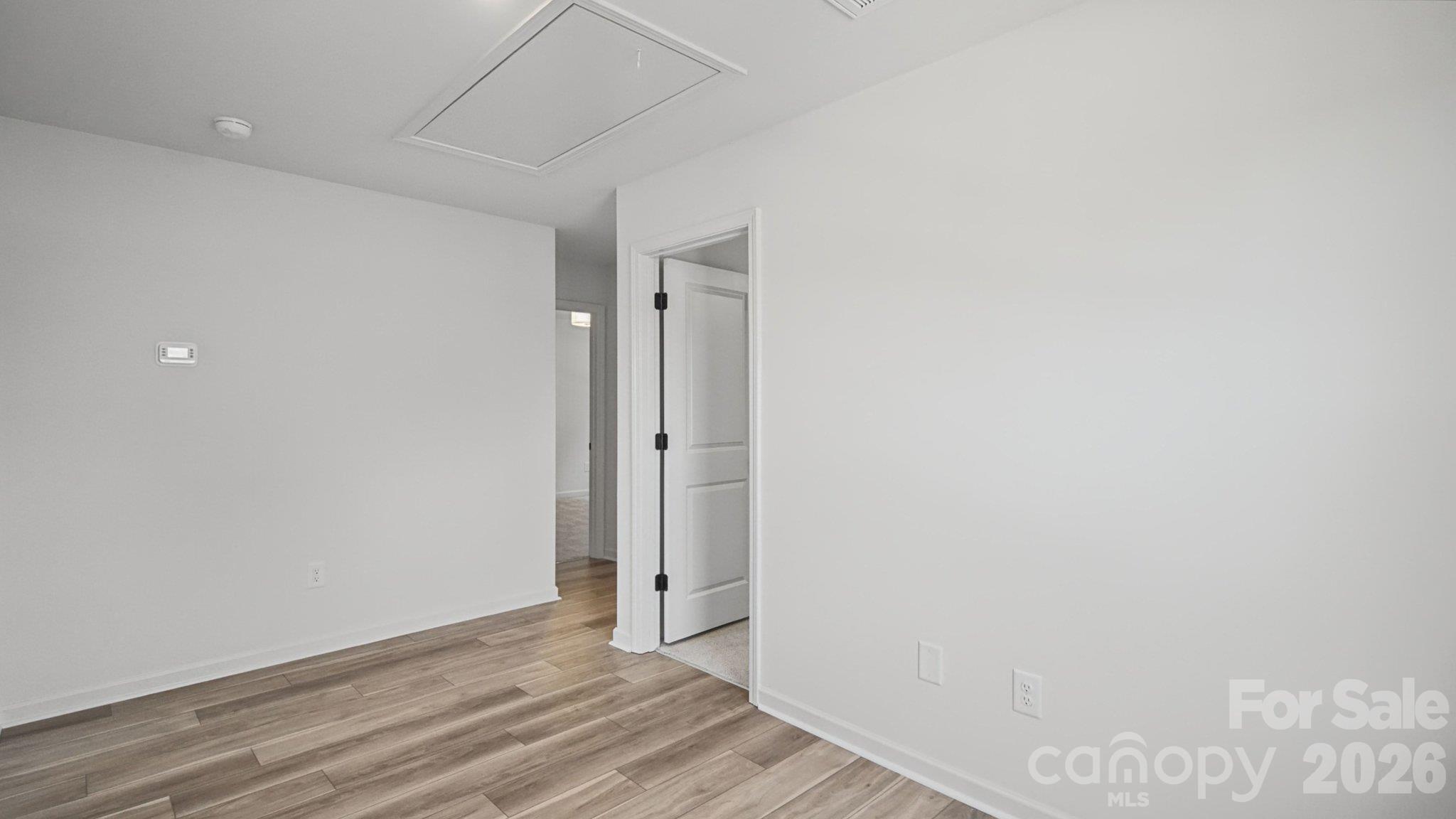 Empty room with wood-look flooring, white walls, and an open doorway.