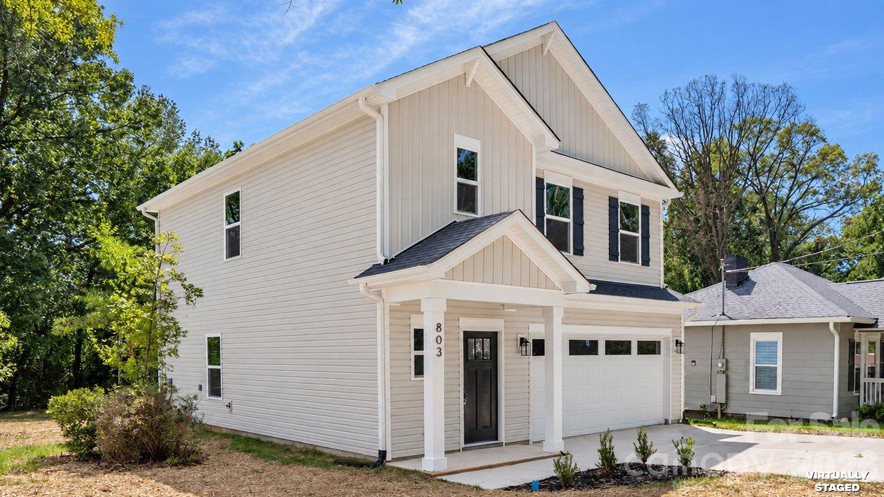 Two-story white-sided home with a covered entry, black front door, and attached garage.