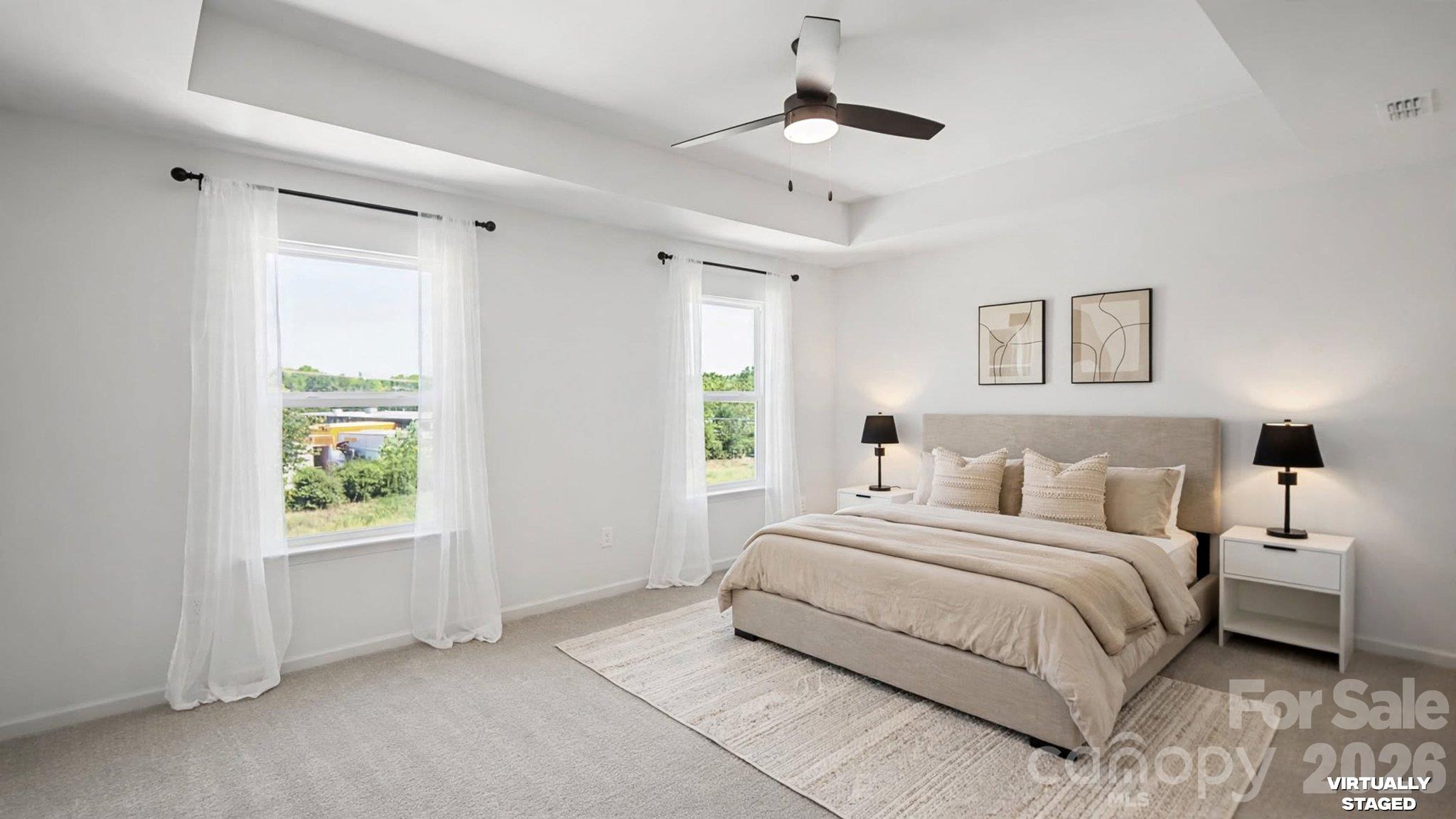 Virtually staged bedroom with a beige bed, two curtained windows, and a ceiling fan.