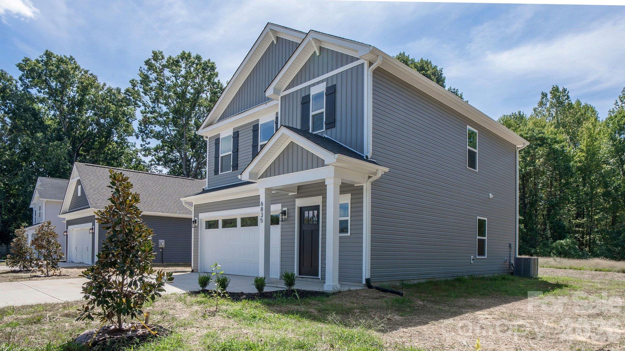 Two-story gray house with white trim, a covered entry, and an attached garage.