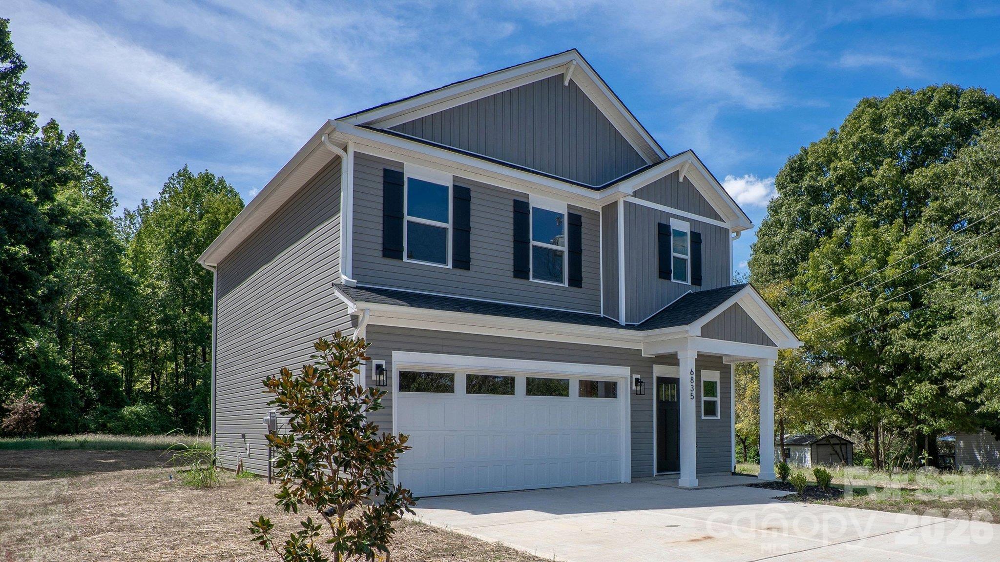 Two-story gray house with white trim, black shutters, and a double garage.