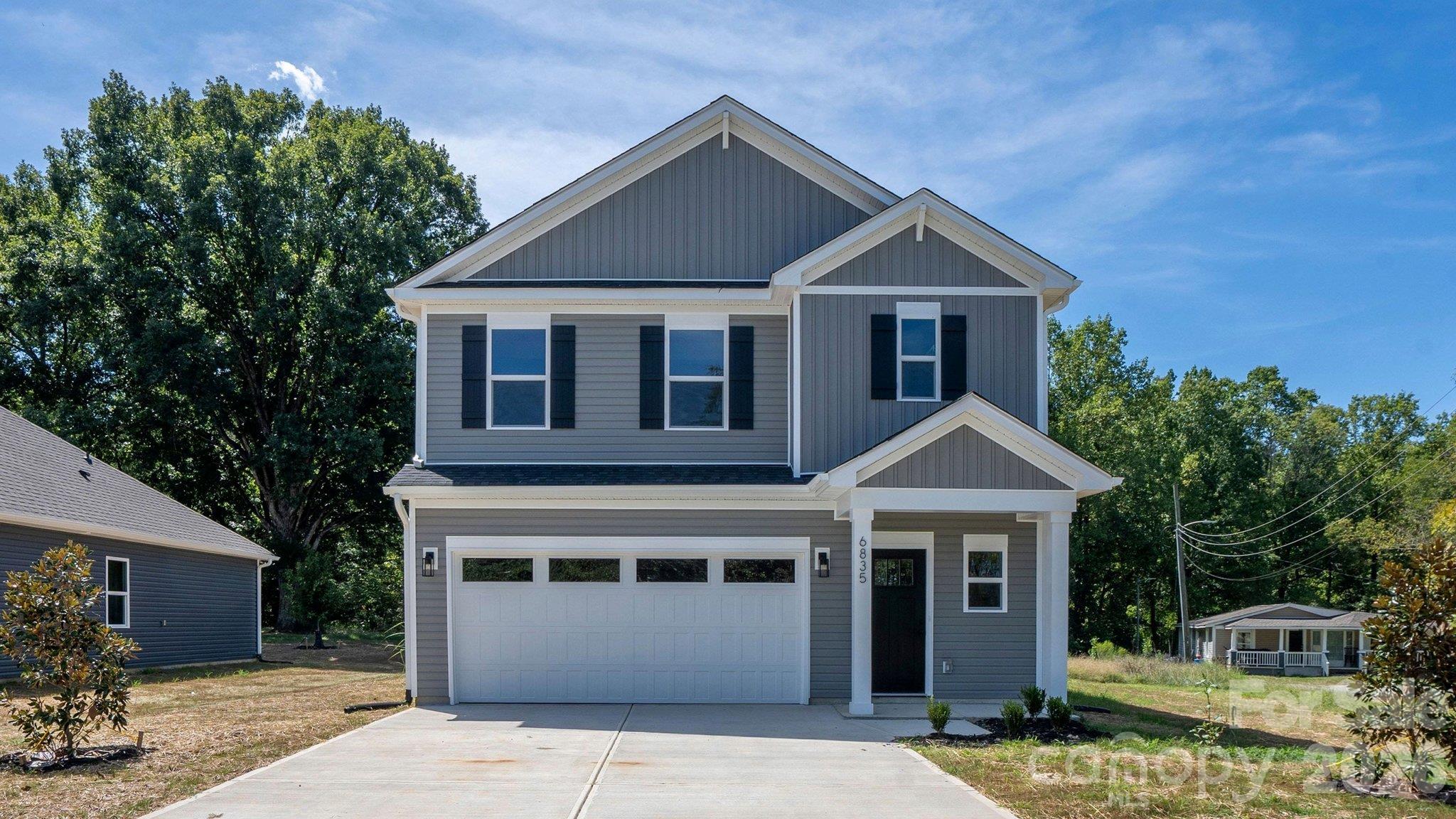 Two-story gray house with white trim, black shutters, and an attached garage.