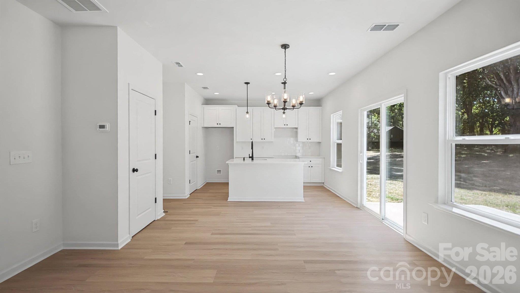 Bright kitchen with white cabinetry, a central island, light wood floors, and sliding glass doors.