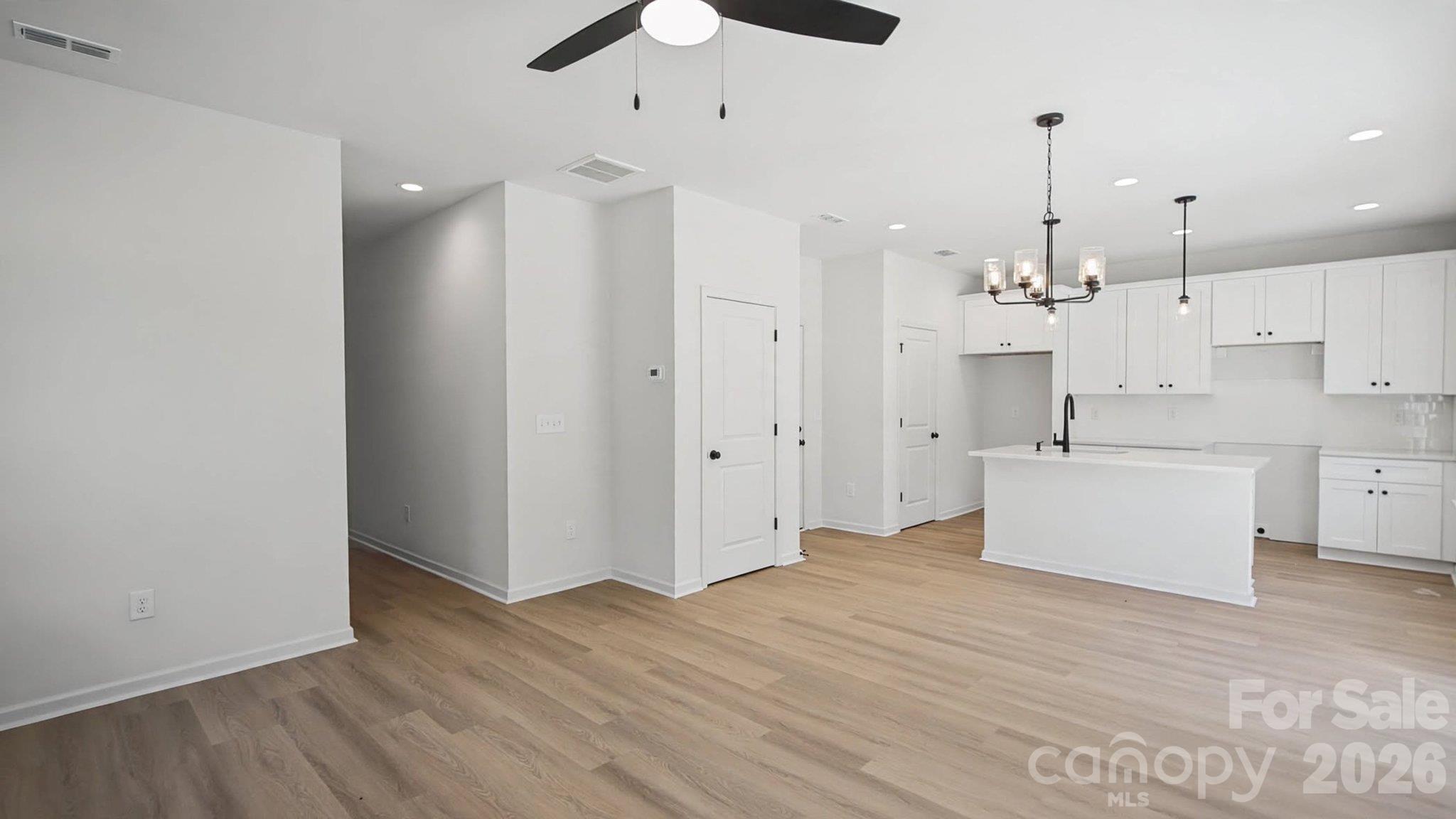 Open-plan kitchen with white cabinets, a large island, and light wood flooring.