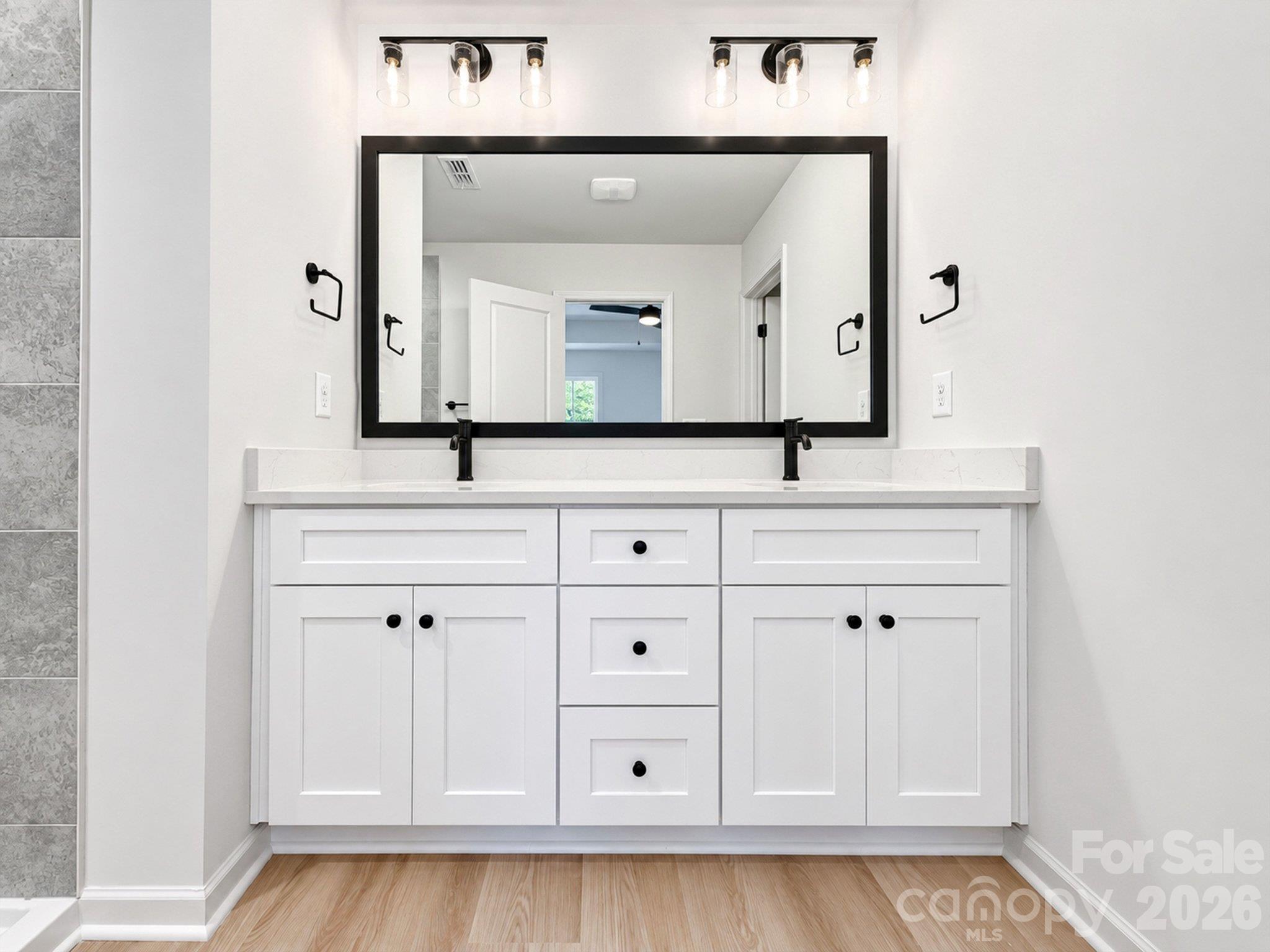 Bathroom with a white double-sink vanity, black fixtures, and a large framed mirror.