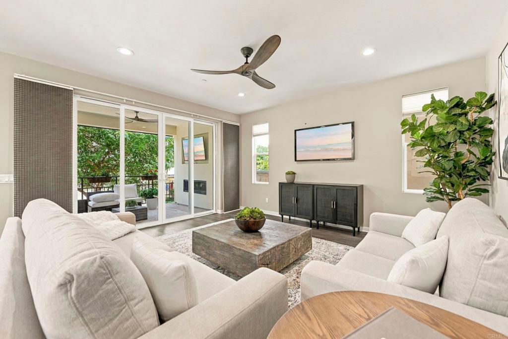 Living room with white sofas, a stone coffee table, and sliding doors to a leafy patio.