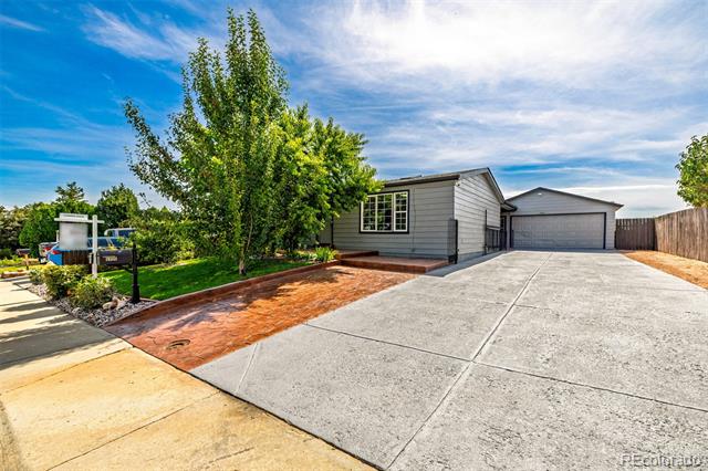 Gray single-story home with a broad concrete driveway, garage, and landscaped front yard.