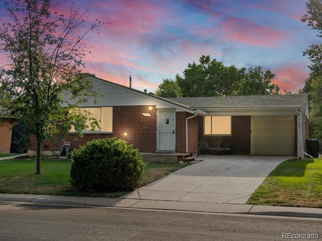 Single-story brick home with an attached garage and concrete driveway at dusk.