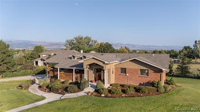 Brick-and-siding home with a covered porch, landscaped yard, and distant mountain views.