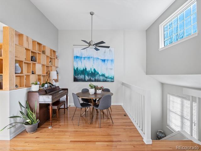Dining area with a round table, piano, built-in shelves, and hardwood floors.