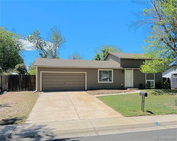 Gray single-story home with an attached garage, wide driveway, and small front lawn.
