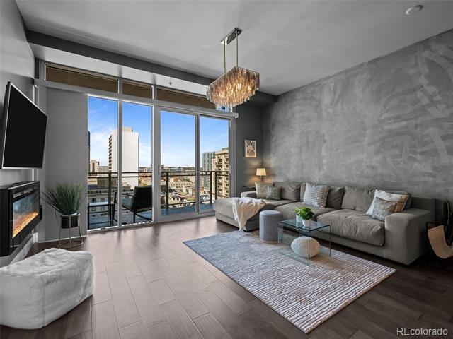 Condo living room with floor-to-ceiling windows overlooking the city and a gray sectional sofa.