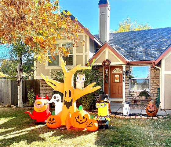 Two-story house with a red front door and Halloween inflatables and pumpkins in the yard.
