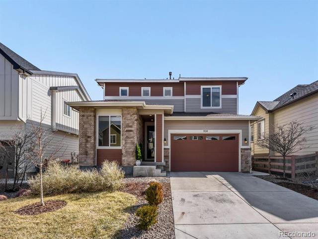 Two-story home with stone-accented entry, reddish-brown garage door, and concrete driveway