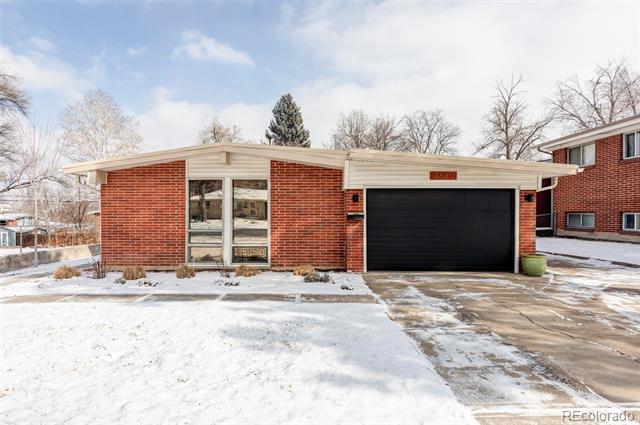 Single-story red brick house with a black double garage door and snow-covered yard.