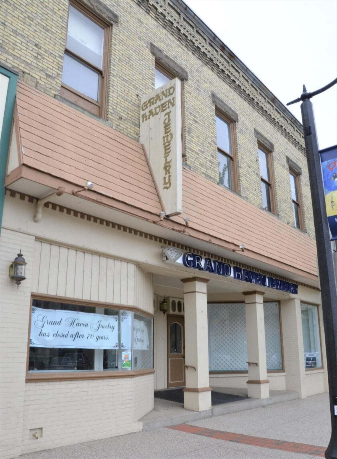 Grand Haven Jewelry storefront with a vertical sign and a notice announcing its closure after 70 years.