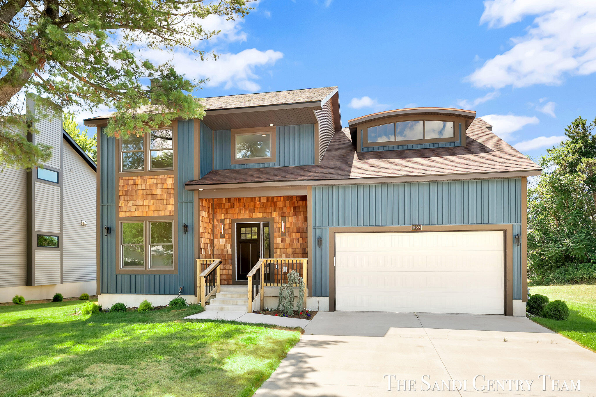 Modern blue two-story house with cedar-shingle accents, covered entry, and attached two-car garage.