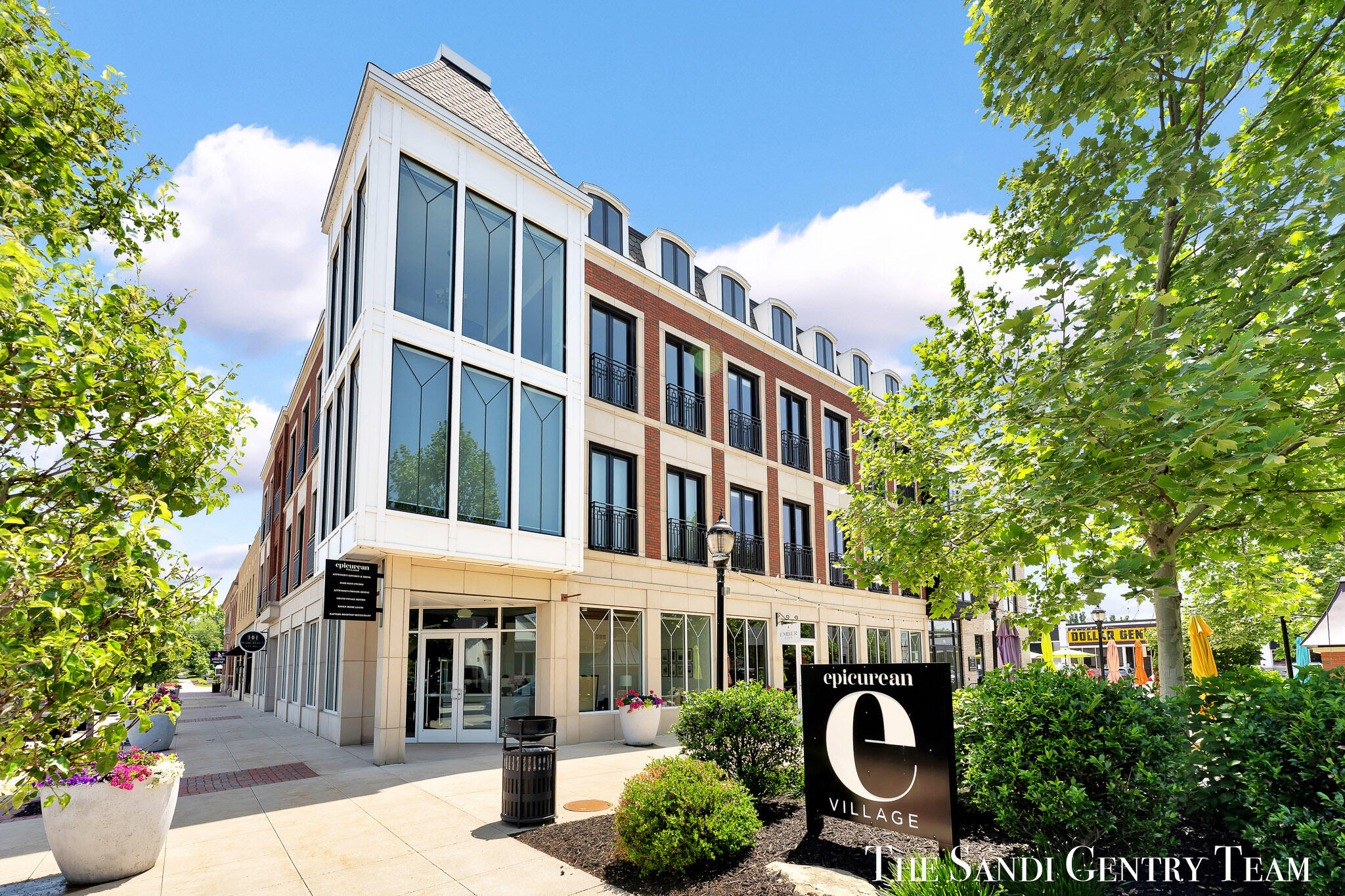 Modern mixed-use building with a red brick facade, large windows, and an E Village sign.