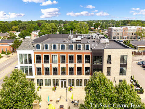 Aerial view of a modern brick-and-glass building with outdoor seating and trees.