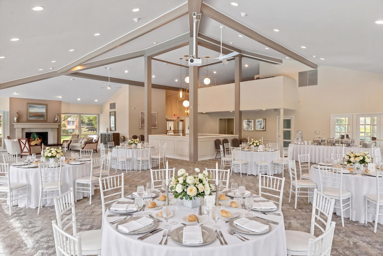 Banquet room with round tables and white chairs beneath a high vaulted ceiling.