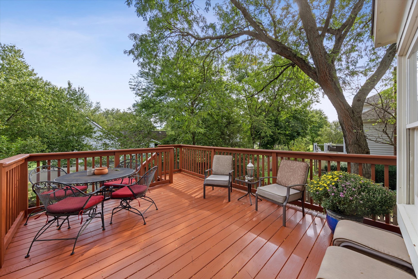 Wood deck with outdoor dining and lounge seating beneath mature trees.