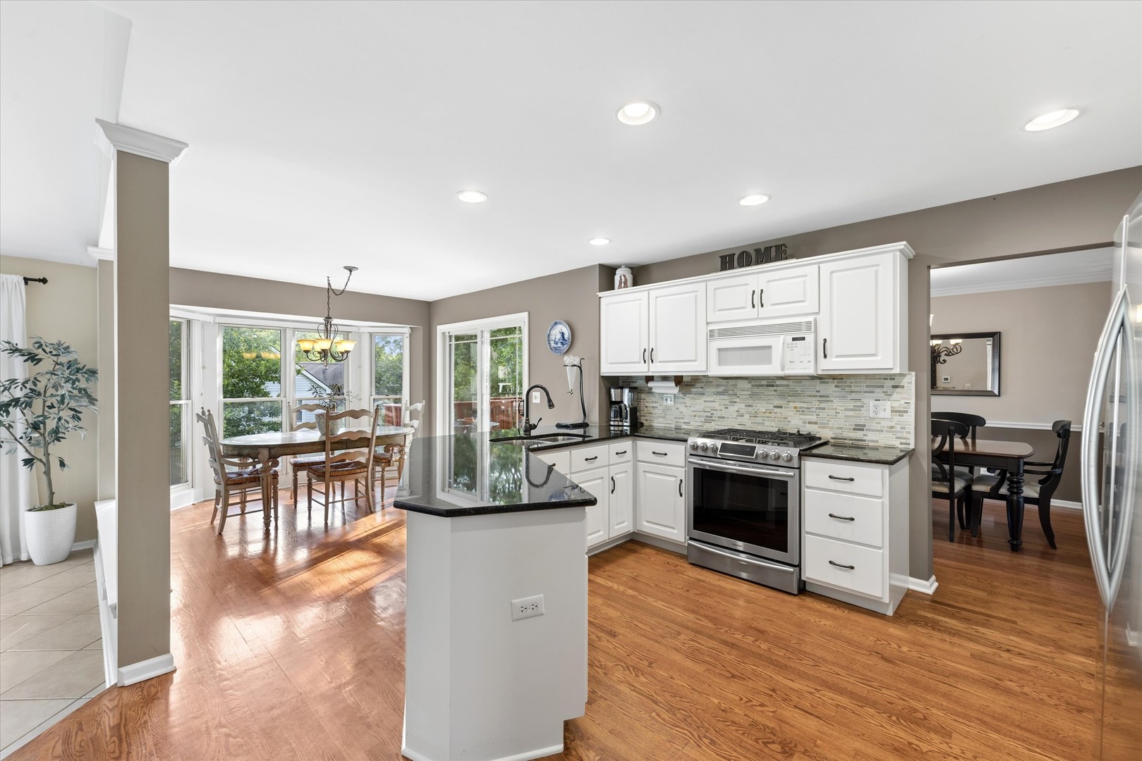 Kitchen with white cabinets, stainless steel appliances, dark countertops, and a peninsula opening to dining areas.