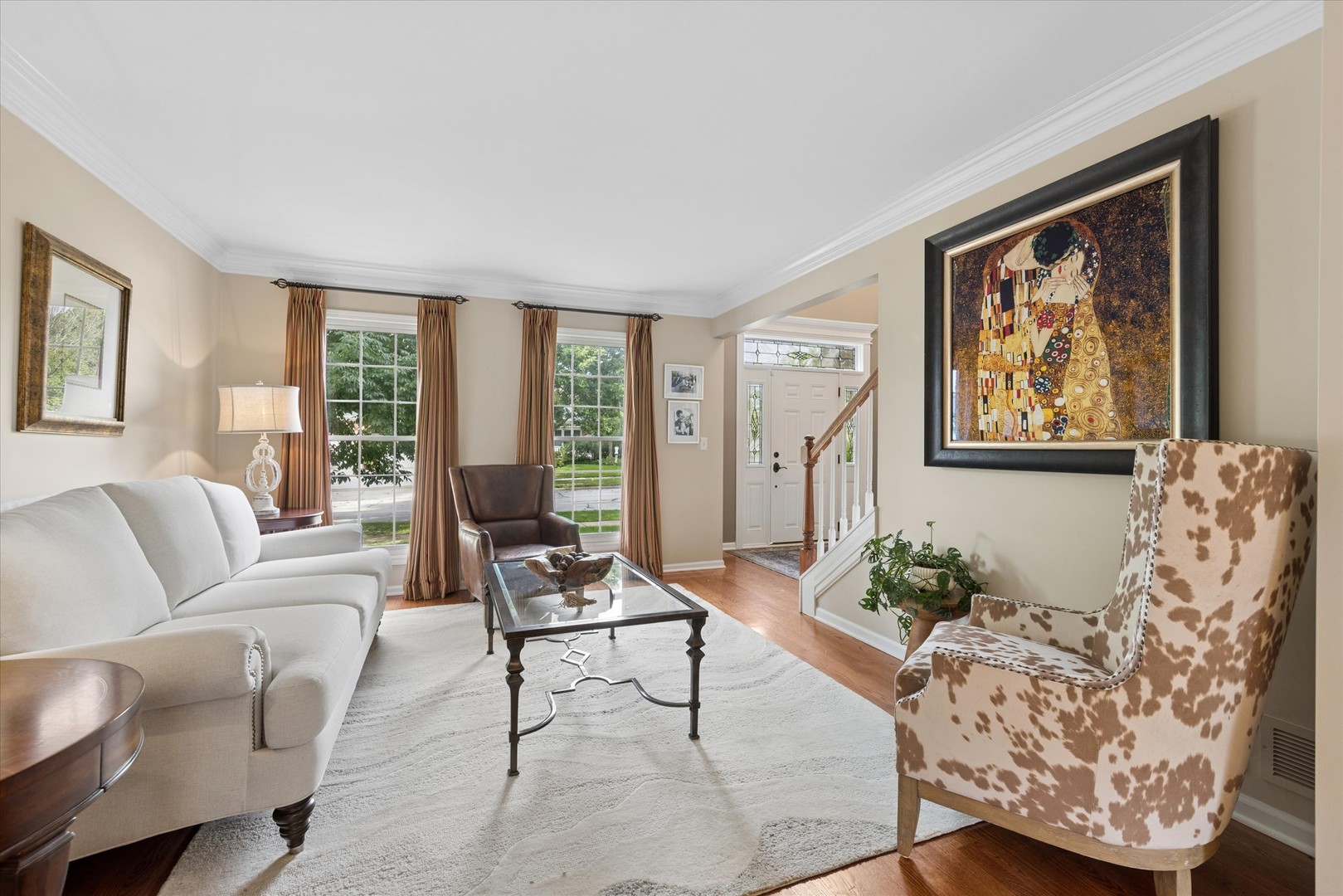 Living room with a white sofa, patterned accent chair, and large framed artwork beside the entryway.