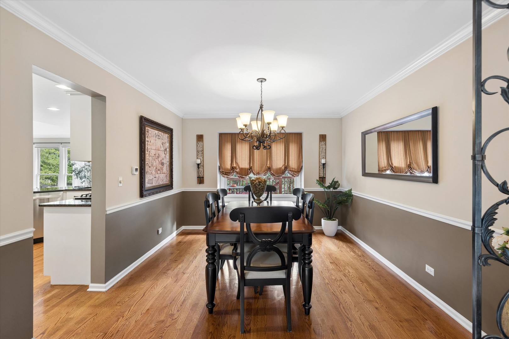Dining room with a dark wood table, black chairs, chandelier, and hardwood floors.
