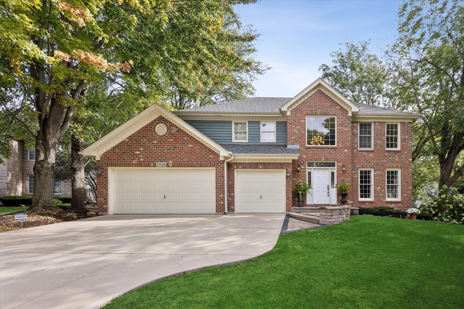 Two-story brick and blue-sided home with a three-car garage and broad front lawn.