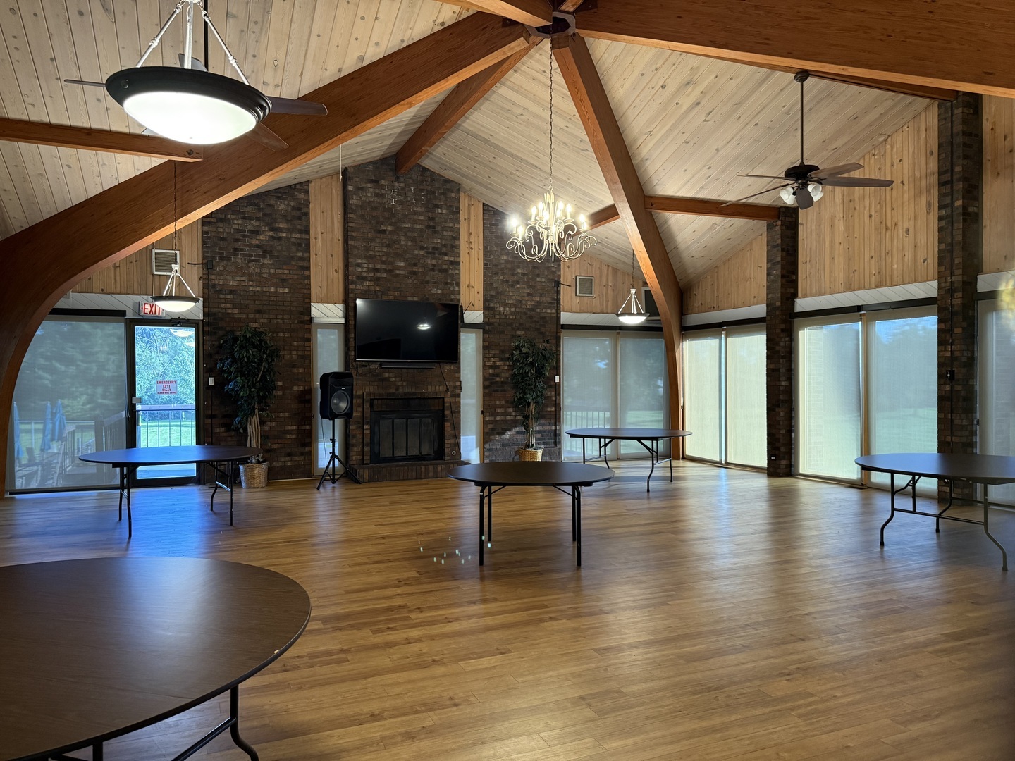 Spacious common room with a vaulted timber ceiling, brick fireplace, and tall windows.
