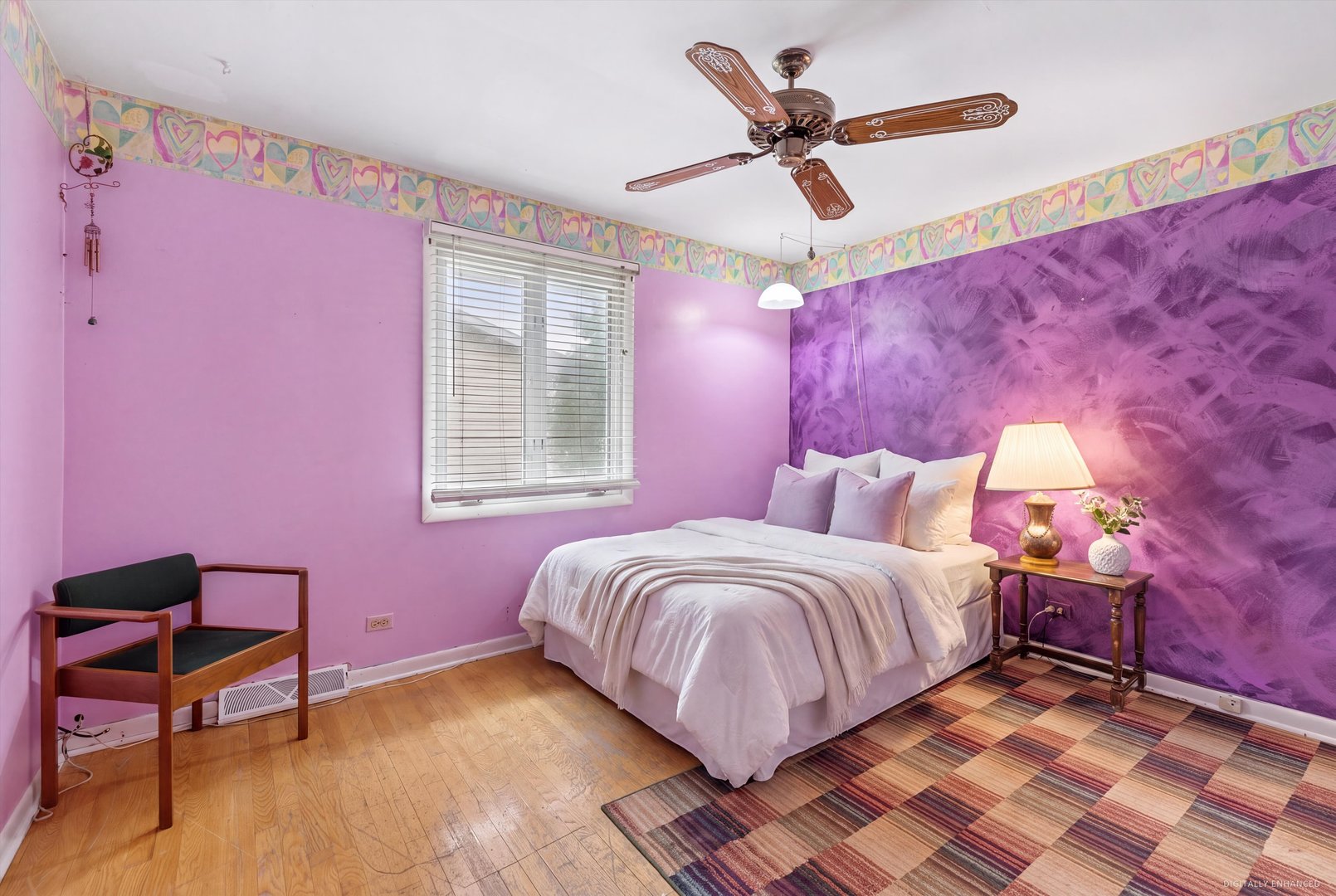 Bedroom with purple walls, a white bed, ceiling fan, and multicolored rug.