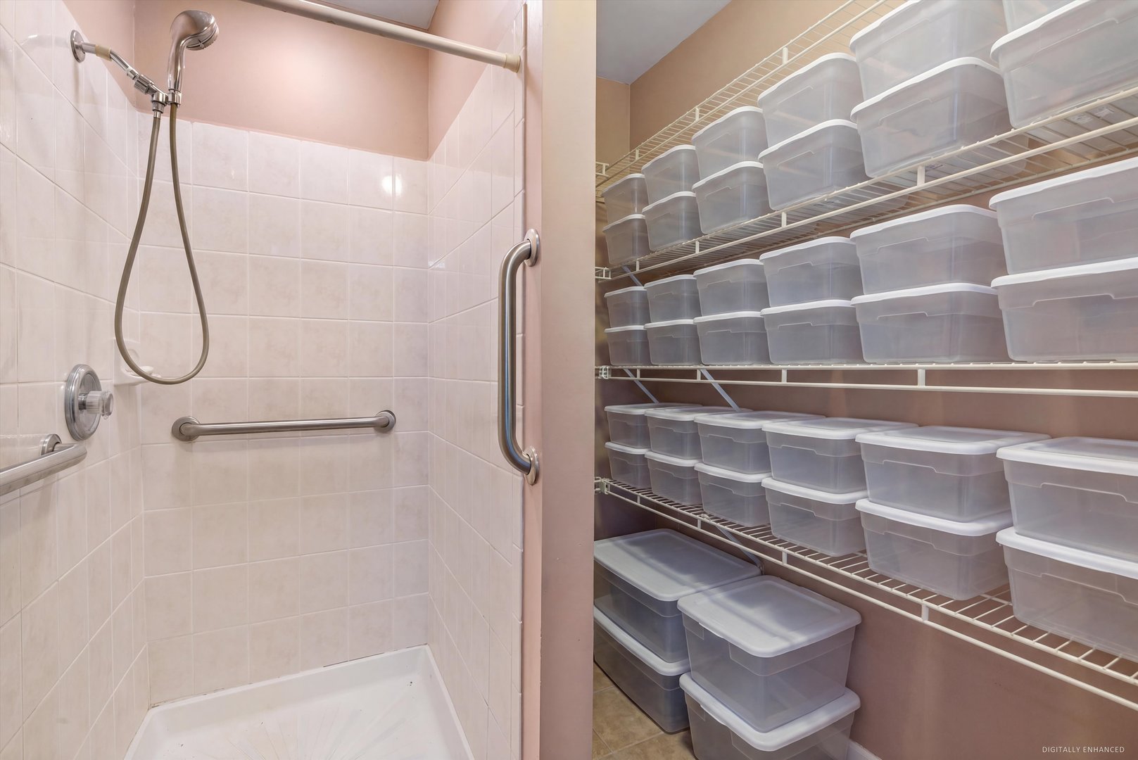 Tiled shower with grab bars beside a closet organized with rows of plastic storage bins.