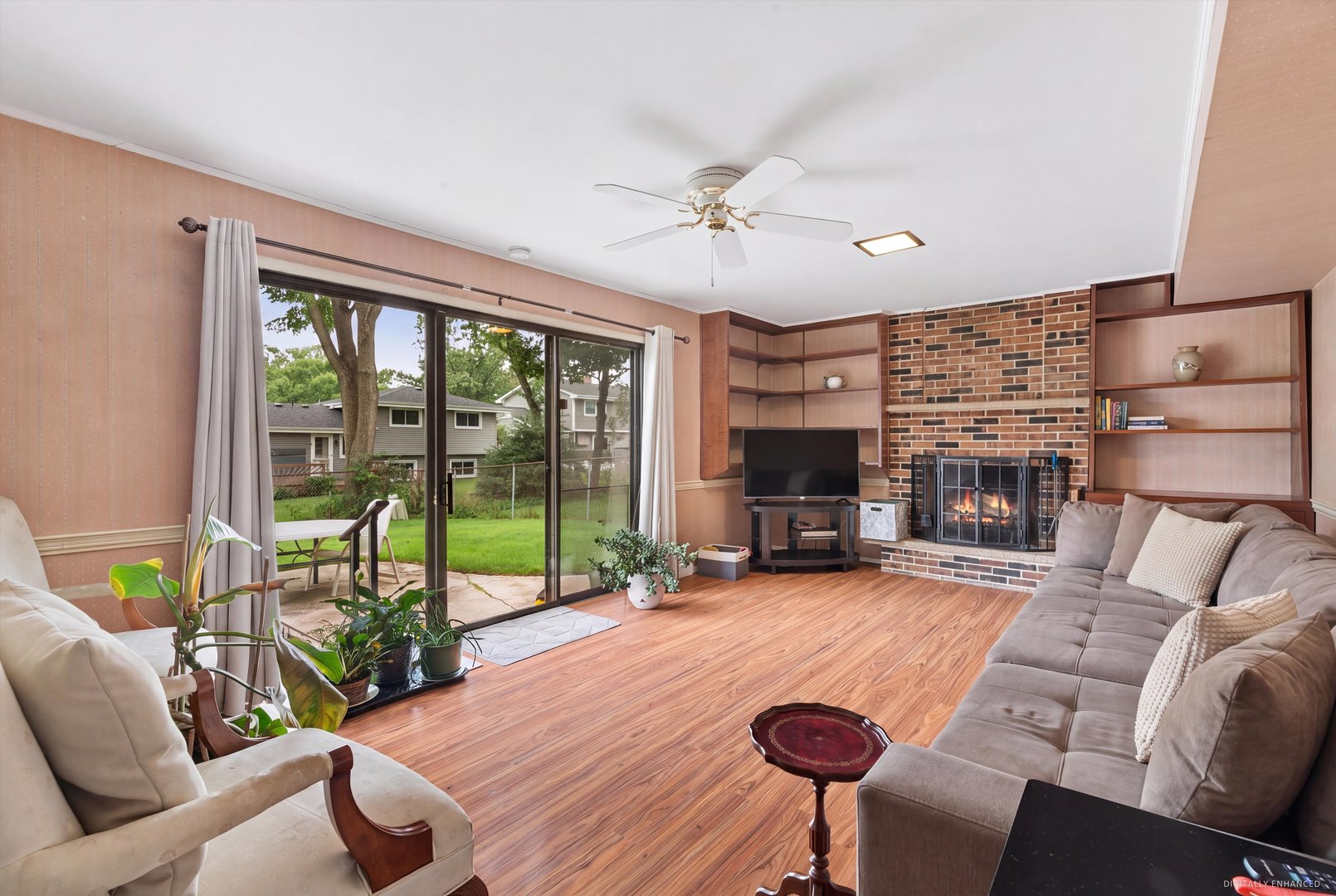 Living room with brick fireplace, built-in shelves, and sliding glass doors to the backyard.